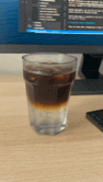 A drink in a glass on a work desk.